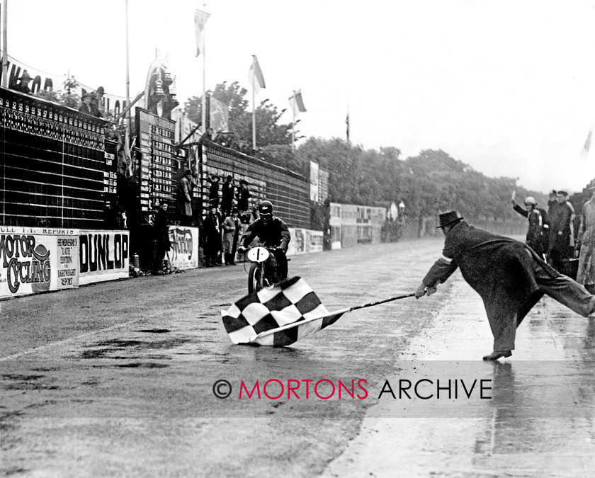 Manx 16A 
 16A – Ted Mellors defies the weather as he takes the chequered linen in the 1939 Lightweight TT. 
 Keywords: 2012, Exhibition of historic images, Manx Grand Prix, Mortons Archive, Mortons Media Group, Mountain Milestones - Memories from Mona's Isle