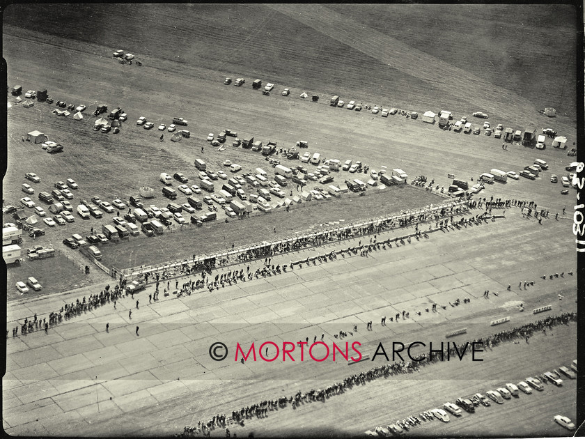 062 glass plate 02 
 An ariel view of the straight and the pits shows the wall of spectators on the opposite side of the track to the pits waiting for the action to begin; bikes are also lined up next to the pits. 
 Keywords: 1963, 2013, Glass plate, June, Mortons Archive, Mortons Media Group, Straight from the plate, The Classic MotorCycle, Thruxton 500 mile race