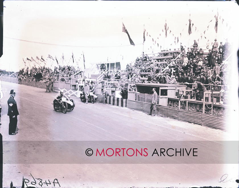 062 FROM THE PLATE 06 
 Len Parker crosses the line to win the last Sidecar TT for nearly 30 years. THe Tinklers' 500cc P&M is stopped at the pit. 
 Keywords: 1925 Sidecar TT, 2011, December, Mortons Archive, Mortons Media Group, Sidecars, Straight from the plate, The Classic MotorCycle