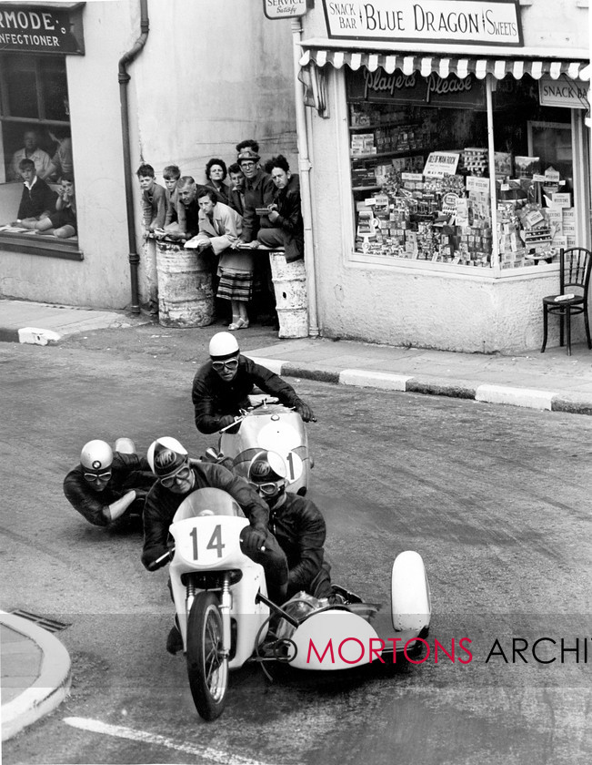 Manx Page 2 
 Page two – No time to stop at the Blue Dragon Café for Ernie Walker, pursued by Helmut Fath, as the turn right at the Manx Arms during the 1959 Sidecar TT. 
 Keywords: 2012, Exhibition of historic images, Manx Grand Prix, Mortons Archive, Mortons Media Group, Mountain Milestones - Memories from Mona's Isle
